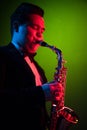 Cute Guy Musician Enjoys Playing the Saxophone, Tenor Saxophone. Neon Light. Close-up Portrait
