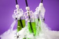 Cute Halloween green drinks for a kids party in spider cobweb on traditional purple background, funny food for seasonal autumn