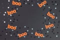 Cute Halloween Layout Border Made of Orange Paper Cut Boo and Shrimmering Silver Confetti of Star Shape on a Black Background. Royalty Free Stock Photo