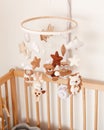 Cute handmade felt mobile on the crib for children. Brown and white colors. Bear, owl, deer, sheep, hedgehog and stars