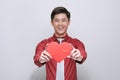 Cute handsome asian holds out a red heart made of paper for Valentine`s Day on a white background with copy space