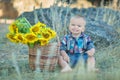 Cute handsome boy wearing jeans close to basket with sunflowers and stones. Royalty Free Stock Photo