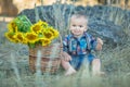 Cute handsome boy wearing jeans close to basket with sunflowers and stones. Royalty Free Stock Photo
