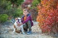 Cute handsome stylish boy enjoying colourful autumn park with his best friend red and white english bull dog. Delightfull