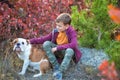 Cute handsome stylish boy enjoying colourful autumn park with his best friend red and white english bull dog.Delightfull