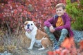 Cute handsome stylish boy enjoying colourful autumn park with his best friend red and white english bull dog.Delightfull