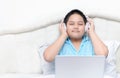 Cute happy Asian boy wearing headphones to listen music from laptop Royalty Free Stock Photo