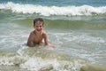 Cute happy baby boy bathes in the sea with waves, vacations. Royalty Free Stock Photo