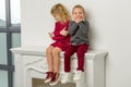 Cute Happy Boy and Girl Sitting Together on Mantelpiece