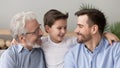 Cute happy boy grandson embracing young father and old grandfather Royalty Free Stock Photo