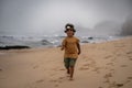 cute happy boy in a headlamp running fast on the beach with the background of the sea in the fog