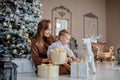 Cute happy boy in santa hat unwrap christmas present box on holiday morning in beautiful room interior. Male child open Xmas gifts Royalty Free Stock Photo