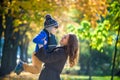 Cute, happy, boy smiling and hugging with his mom among yellow leaves. Little child having fun with mother in autumn park. Concept Royalty Free Stock Photo