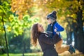 Cute, happy, boy smiling and hugging with his mom among yellow leaves. Little child having fun with mother in autumn park. Concept Royalty Free Stock Photo