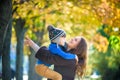 Cute, happy, boy smiling and hugging with his mom among yellow leaves. Little child having fun with mother in autumn park. Concept Royalty Free Stock Photo