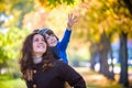 Cute, happy, boy smiling and hugging with his mom among yellow leaves. Little child having fun with mother in autumn park. Concept Royalty Free Stock Photo