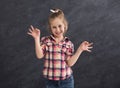 Happy little girl grimacing at grey background