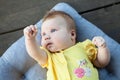 Cute happy one month baby girl in yellow clothing lying and playing