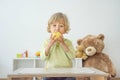 Cute happy child boy having fun eating a big fresh yellow apple fruit at home. Children healthy eating and lifestyle conceptual Royalty Free Stock Photo