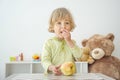 Cute happy child boy having fun eating a big fresh yellow apple fruit at home. Children healthy eating and lifestyle conceptual Royalty Free Stock Photo