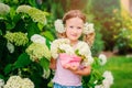 Cute happy child girl with hydrangea flowers bouquet in summer garden Royalty Free Stock Photo