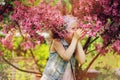 Cute happy child girl in jeans vest enjoying spring near blooming crab apple tree in country garden Royalty Free Stock Photo