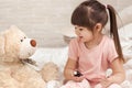Cute child girl playing doctor with teddy bear Royalty Free Stock Photo