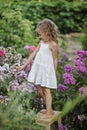 Cute happy child girl playing in summer blooming garden