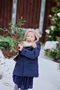 Cute happy child girl playing in winter snowy garden with basket of fir branches Royalty Free Stock Photo