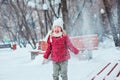 Cute happy child girl throwing snow and laughing on the walk in winter park Royalty Free Stock Photo