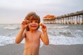 Cute, happy child holding shell at the beach. Cute little boy at tropical beach holding sand shell. Summer travel and Royalty Free Stock Photo