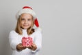 Cute happy child Santa giving red Xmas gift on white studio wall background