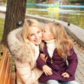 Cute happy daughter kissing her mother in park Royalty Free Stock Photo