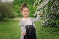 Cute happy dreamy toddler child girl walking in blooming spring garden, celebrating easter outdoor