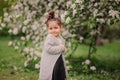 Cute happy dreamy toddler child girl walking in blooming spring garden, celebrating easter outdoor