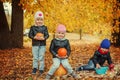 Three happy friends kids in autumn park with small pumpkins. Royalty Free Stock Photo