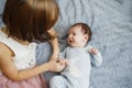 Cute happy girl holding her newborn baby brother. Gray background. Pretty baby boy in blue clothes Royalty Free Stock Photo