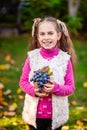 Cute happy girl holding ripe grapes in the garden on a sunny autumn day Royalty Free Stock Photo