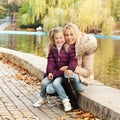 Cute happy girl hugging her mother outdoor in autumn park Royalty Free Stock Photo