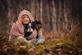 Cute happy kid girl with her dog on cozy autumn walk in forest