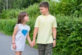 Cute happy kids are walking in the summer park holding hands