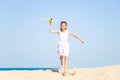 Cute happy laughing little girl wearing a white dress running on the sandy beach by the sea and playing with Royalty Free Stock Photo