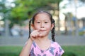 Cute happy little Asian child girl in garden with pointing at camera. Portrait smiling kid in summer park. Focus at children face Royalty Free Stock Photo