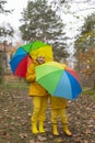 Cute happy little boy and a girl - brother and sister - in identical yellow costumes and hats walking in the forest with rainbow- Royalty Free Stock Photo