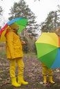 Cute happy little boy and a girl - brother and sister - in identical yellow costumes and hats walking in the forest with rainbow- Royalty Free Stock Photo