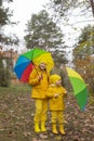 Cute happy little boy and a girl - brother and sister - in identical yellow costumes and hats walking in the forest with rainbow- Royalty Free Stock Photo