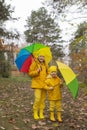 Cute happy little boy and a girl - brother and sister - in identical yellow costumes and hats walking in the forest with rainbow- Royalty Free Stock Photo