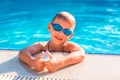 Cute happy little boy in goggles swimming in the swimming pool