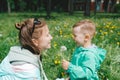 Cute happy little boy in green jacket takes white dandelion from mother`s hands Royalty Free Stock Photo