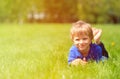 Cute happy little boy lying in green grass on spring Royalty Free Stock Photo